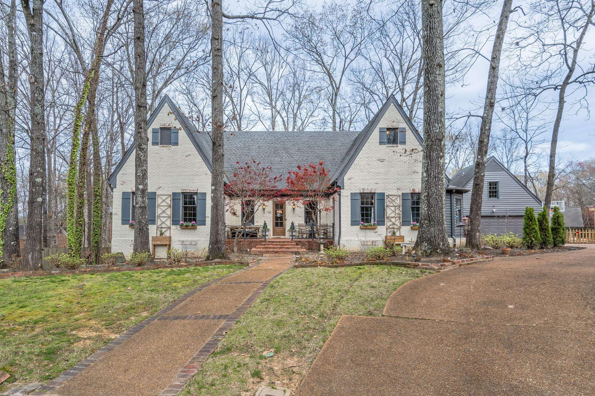 a front view of a house with garden and trees