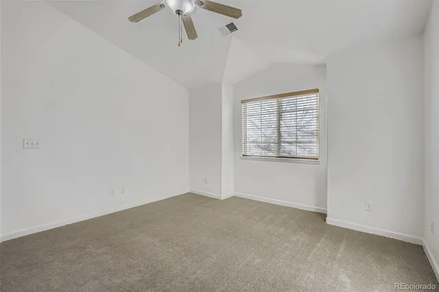 an empty room with chandelier fan and windows