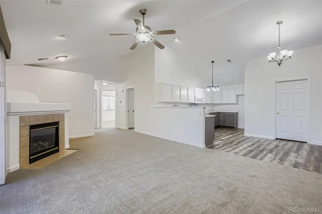 a view of kitchen and empty room with fireplace