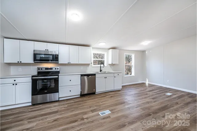 a large kitchen with cabinets wooden floor and stainless steel appliances