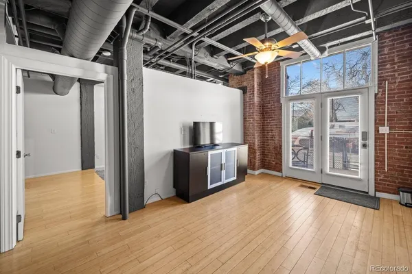 a view of an empty room with wooden floor and a kitchen