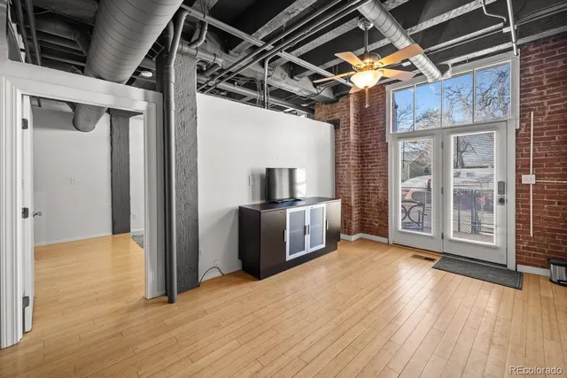 a view of an empty room with wooden floor and a kitchen