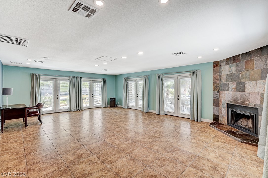 4153 Woodcrest Road Las Vegas, NV 89121 - Photo 24 of 58 A spacious room features multiple sets of French doors, an elegant tile fireplace, and durable tile flooring throughout.