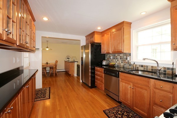 43 Boulder Brook Road Wellesley, MA 02481 - Photo 6 of 23 a kitchen with stainless steel appliances granite countertop a refrigerator a sink dishwasher a stove and a dining table with wooden floor