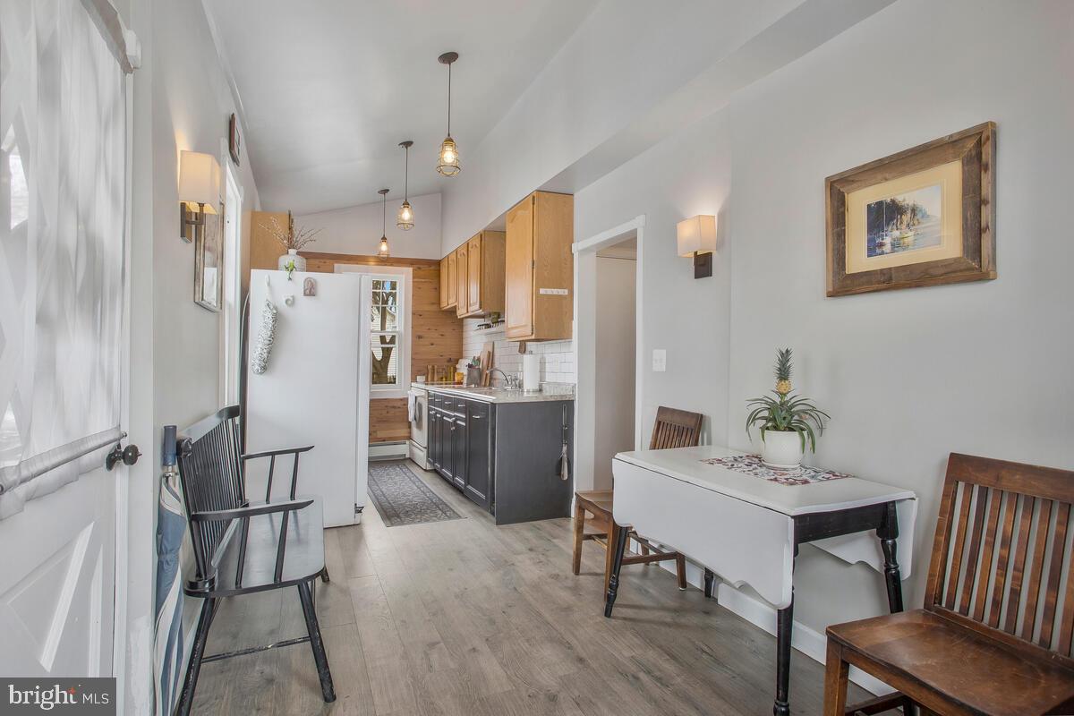 1724 Quantico Road Edgewater, MD 21037 - Photo 18 of 58 a kitchen with stainless steel appliances a refrigerator a sink dishwasher a dining table and chairs with wooden floor