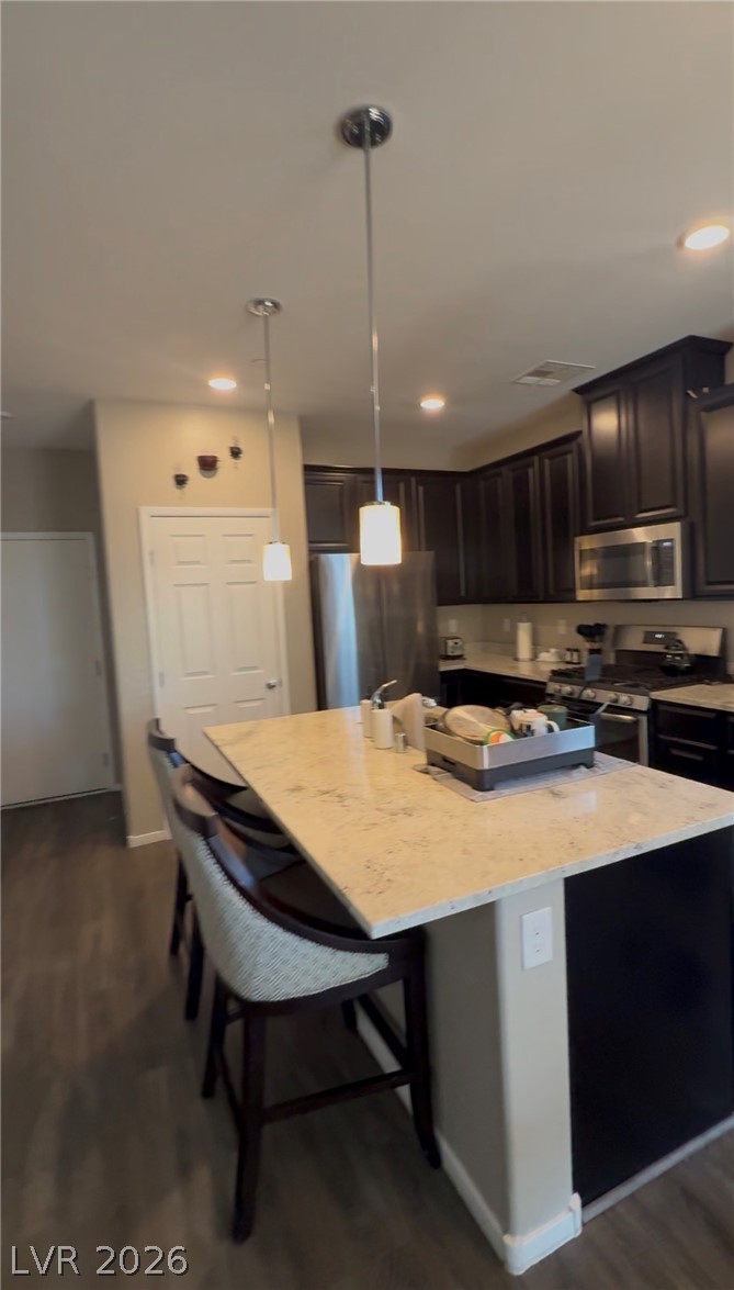 A contemporary kitchen showcasing dark wood cabinetry, stainless steel appliances, and a central island with bar seating.