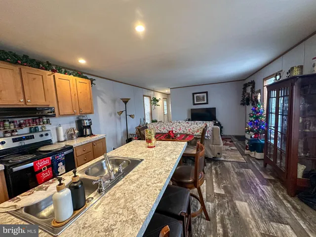 a large kitchen with a stove a refrigerator sink dishwasher a dining table and chairs with wooden floor