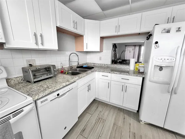 a kitchen with granite countertop white cabinets and white appliances