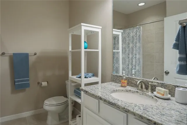 a bathroom with a granite countertop sink a toilet and a mirror