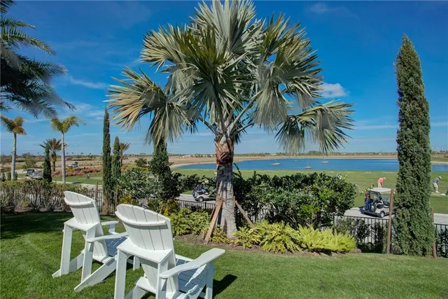 a sign board with a house and trees in the background