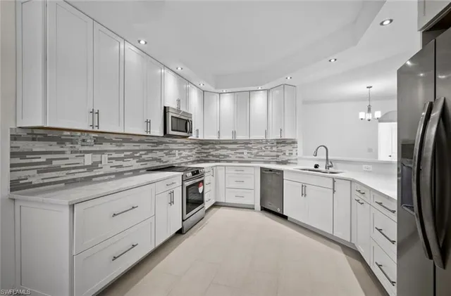 a kitchen with granite countertop white cabinets sink and stainless steel appliances