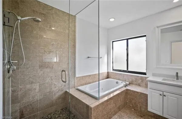 a bathroom with a tub shower sink and mirror