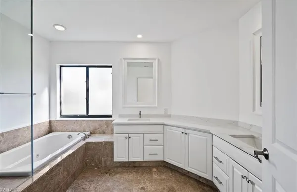 a bathroom with a tub a sink and a window