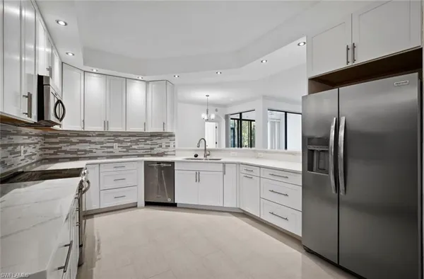 a kitchen with white cabinets stainless steel appliances and a window