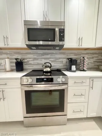 a stove top oven sitting inside of a kitchen and white cabinets