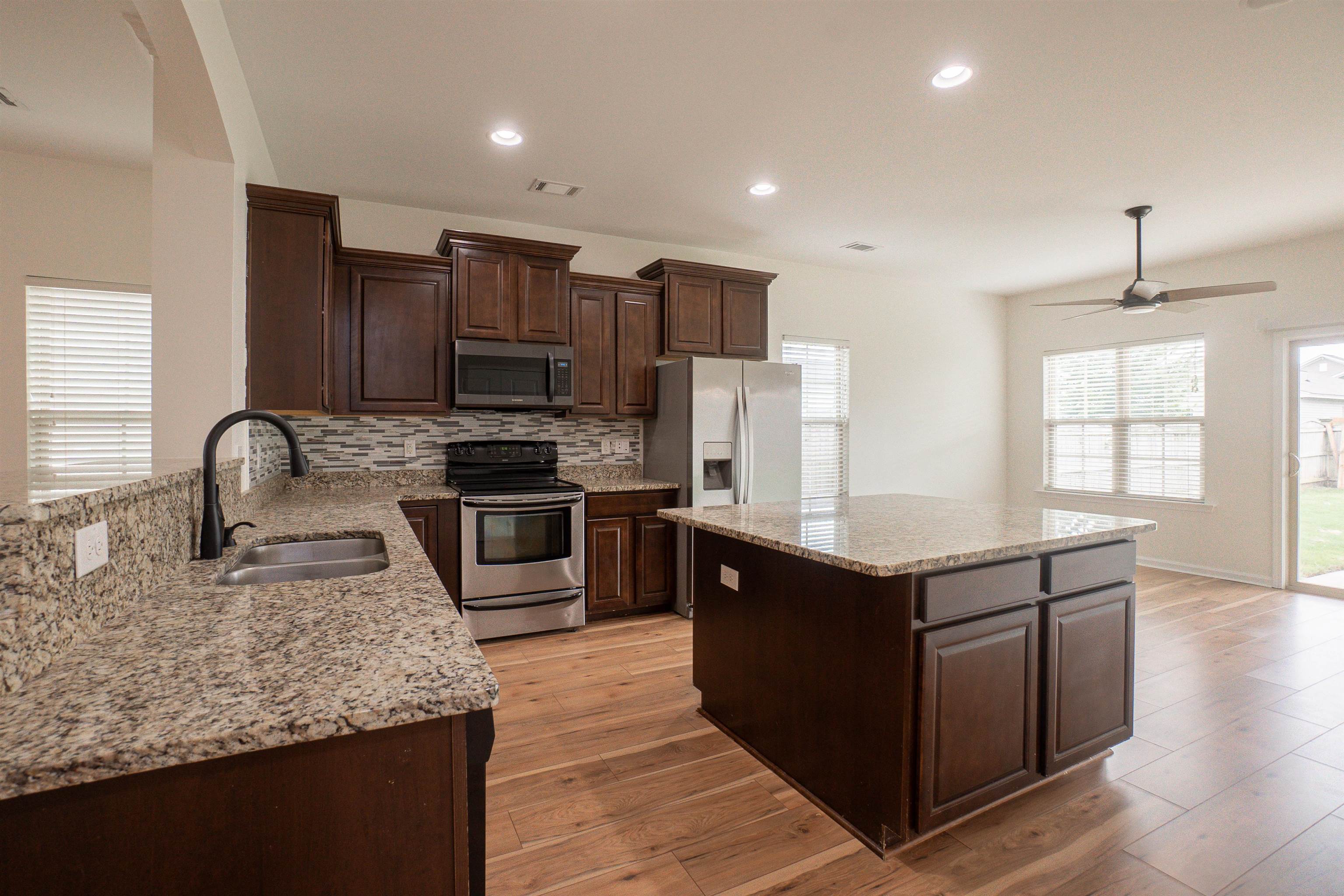 1752 Musket Trail Sumter, SC 29150 - Photo 6 of 37 Kitchen with dark brown cabinetry, appliances with stainless steel finishes, light stone countertops, light wood-style flooring, and recessed lighting