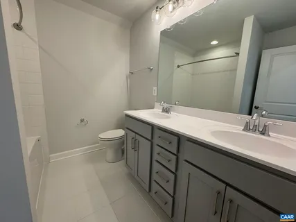 a bathroom with a double vanity sink toilet and mirror