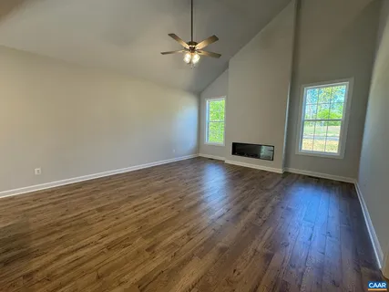 an empty room with wooden floor chandelier fan and windows