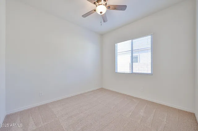 an empty room with a chandelier fan and windows