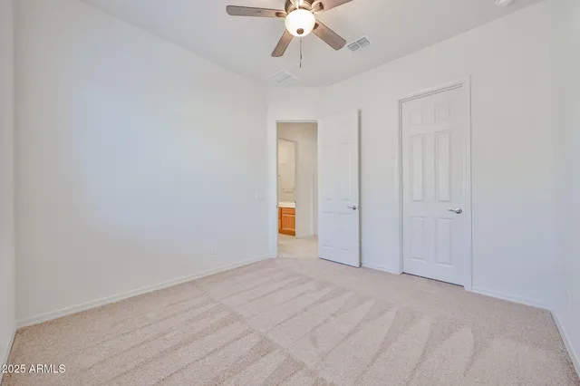 a view of an empty room and chandelier fan