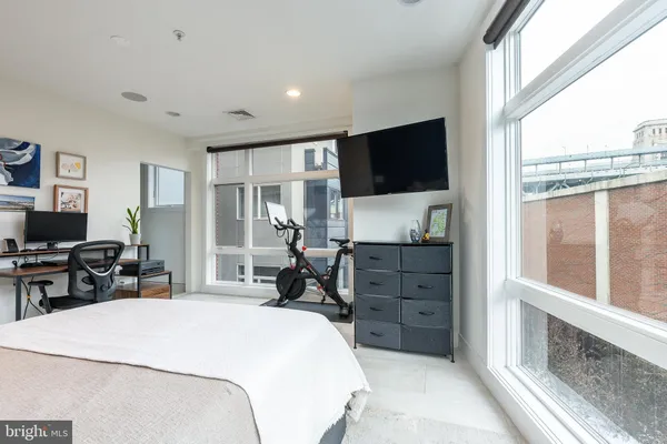 a spacious bedroom with a bed and a flat tv screen next to a large window