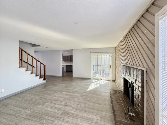 a view of an empty room with wooden floor and a fireplace