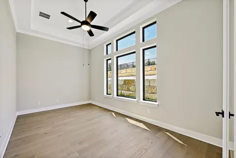 an empty room with ceiling fan and windows