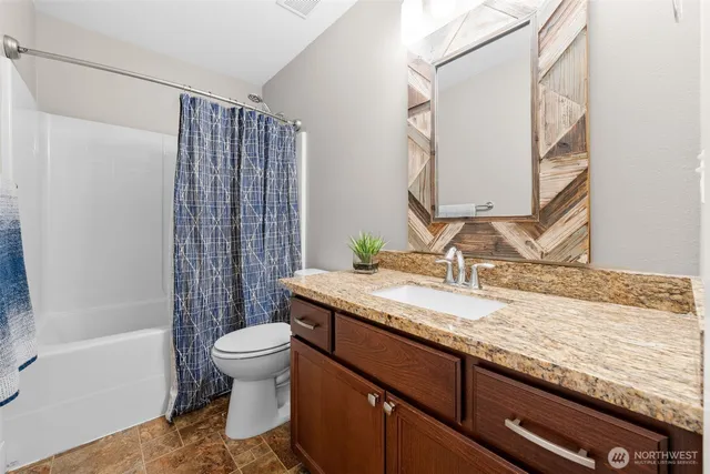a bathroom with a granite countertop sink a toilet and shower