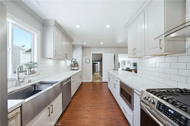 a large kitchen with stainless steel appliances granite countertop a lot of counter space and wooden floor