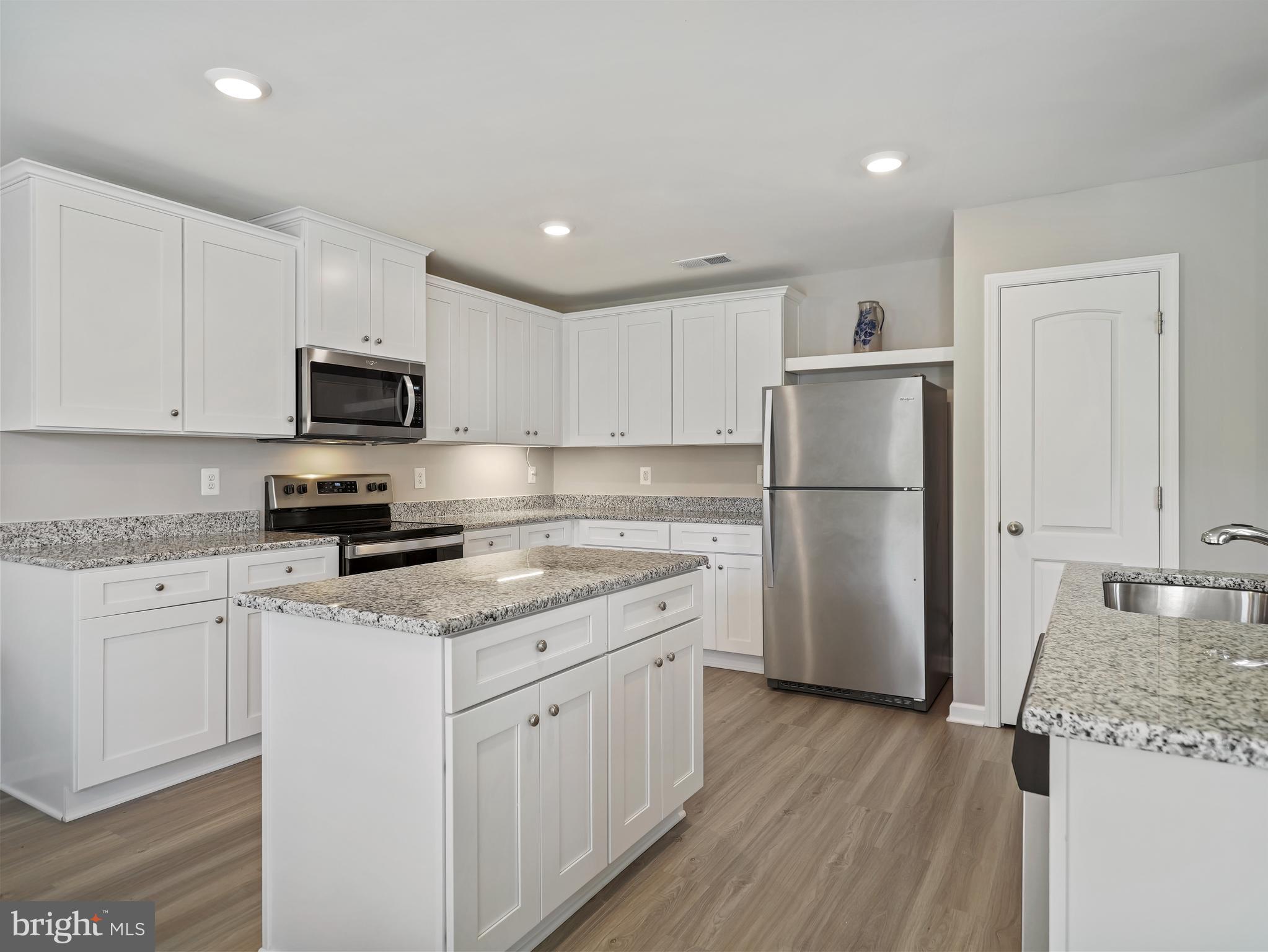 104 Rappahannock Run Falling Waters, WV 25419 - Photo 3 of 41 a kitchen with granite countertop a refrigerator a sink a stove a microwave and wooden floor
