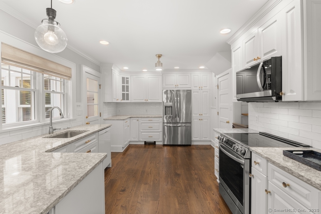 223 Middlesex Road Darien, CT 06820 - Photo 4 of 24 a kitchen with stainless steel appliances granite countertop a sink a stove top oven a refrigerator and dishwasher with wooden floor