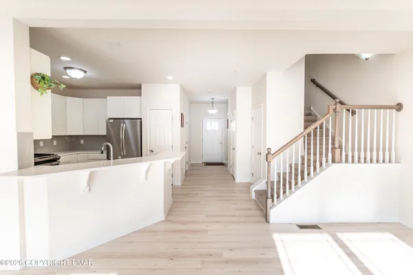 a view of a kitchen with kitchen island a sink wooden floor and a living room view