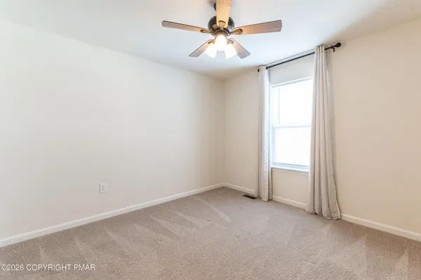 an empty room with windows and fan