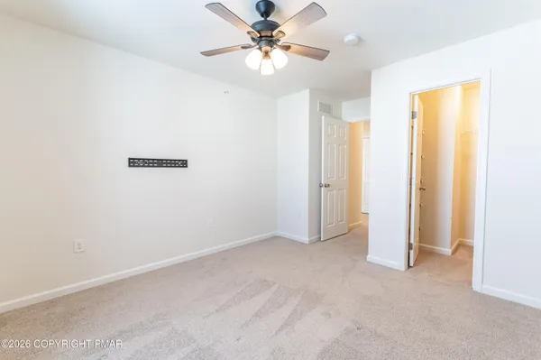 an empty room with closet and a chandelier fan