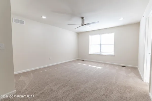 an empty room with a window and ceiling fan