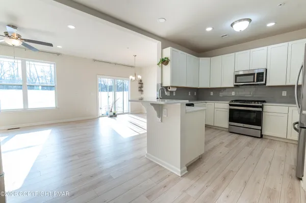 a kitchen with stainless steel appliances a white stove top oven a sink a window and white cabinets