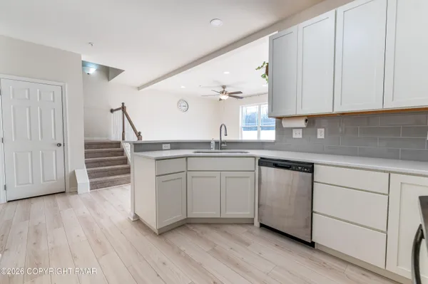 a kitchen with stainless steel appliances granite countertop a sink a stove and cabinets with wooden floor
