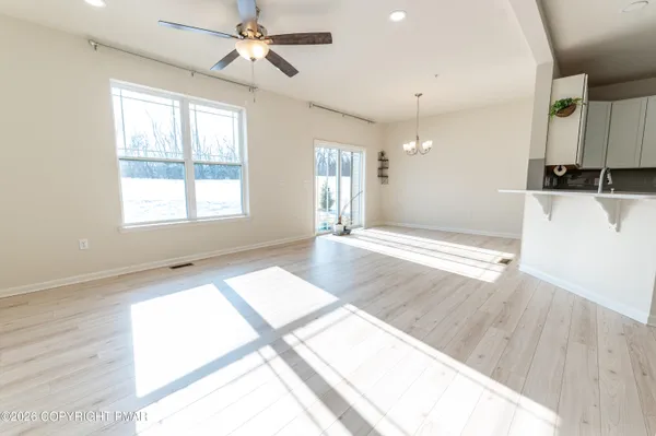 a view of an empty room with window and wooden floor