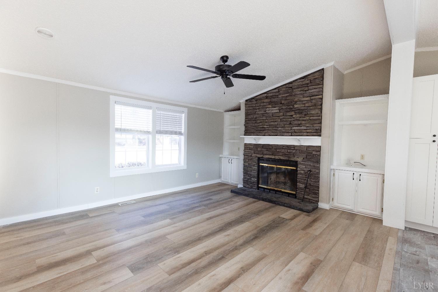 2540 Goode Road Goode, VA 24556 - Photo 6 of 37 an empty room with windows a fireplace and wooden floor
