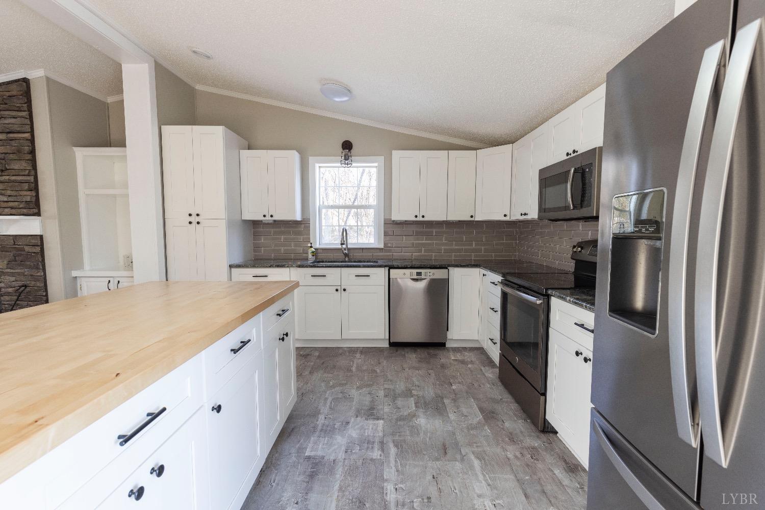 2540 Goode Road Goode, VA 24556 - Photo 10 of 37 a large kitchen with a stove top oven a sink a refrigerator and white cabinets with wooden floor