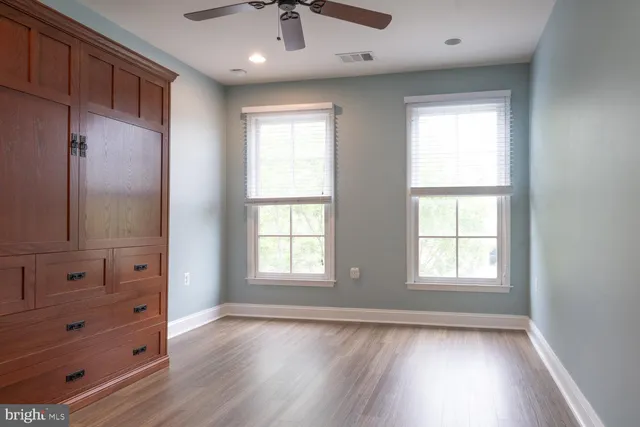 an empty room with wooden floor cabinet and windows