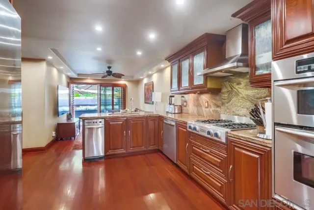 a large kitchen with stainless steel appliances granite countertop a stove and a wooden floors