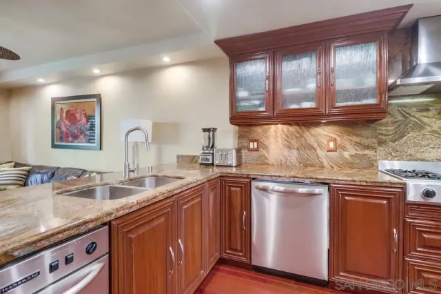 a kitchen with stainless steel appliances granite countertop a sink and wooden cabinets