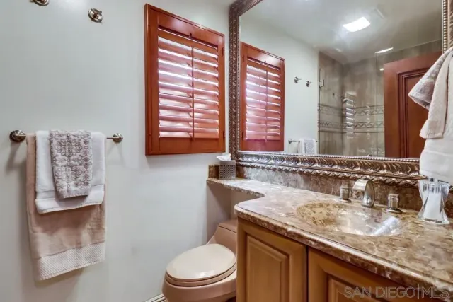 a bathroom with a granite countertop sink toilet and mirror