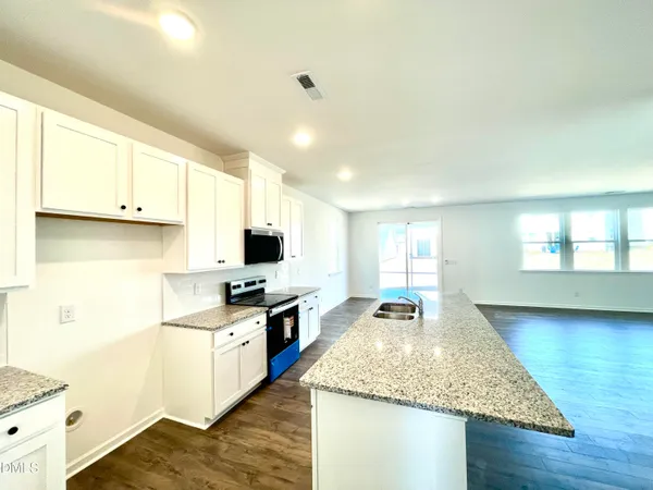 a kitchen with granite countertop a sink stove and cabinets