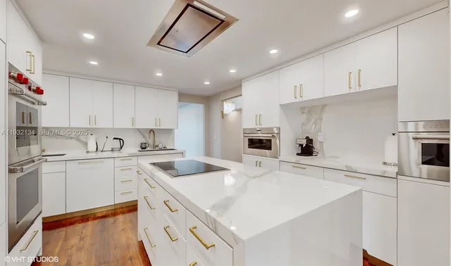 a kitchen with a sink a stove a refrigerator and white cabinets