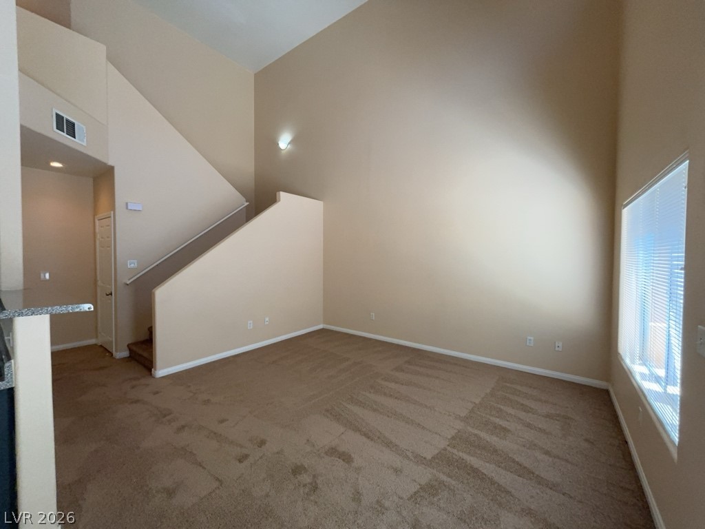 4915 East Russell Road, Unit 145 Las Vegas, NV 89120 - Photo 2 of 13 Unfurnished living room featuring a high ceiling and light colored carpet