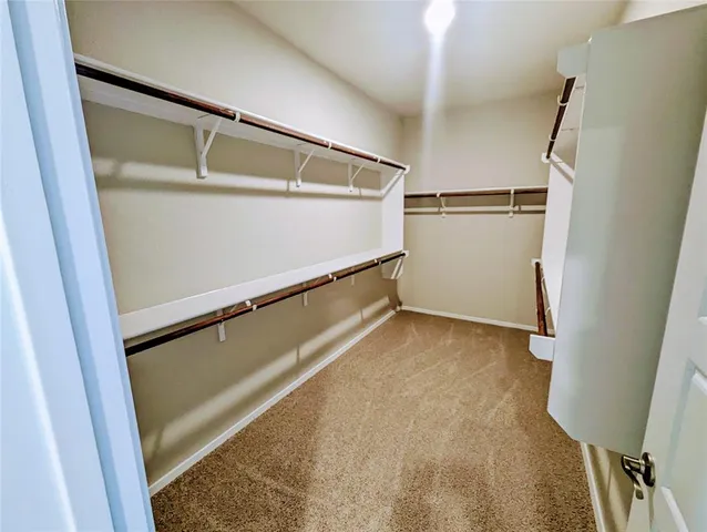 a view of walk in closet with clothes and white walls