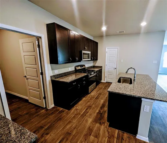 a kitchen with kitchen island granite countertop stainless steel appliances and wooden cabinets