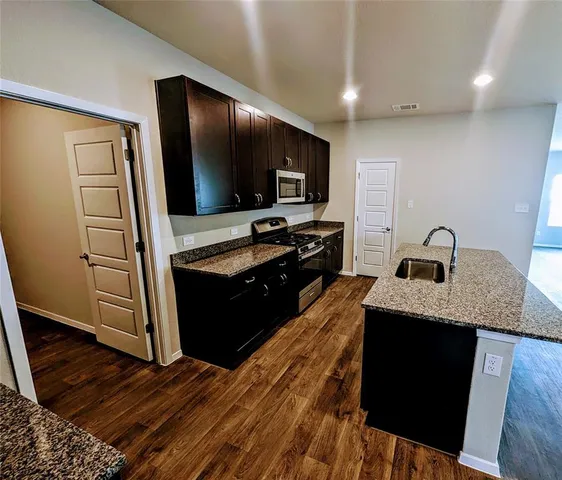 a kitchen with kitchen island granite countertop stainless steel appliances and wooden cabinets